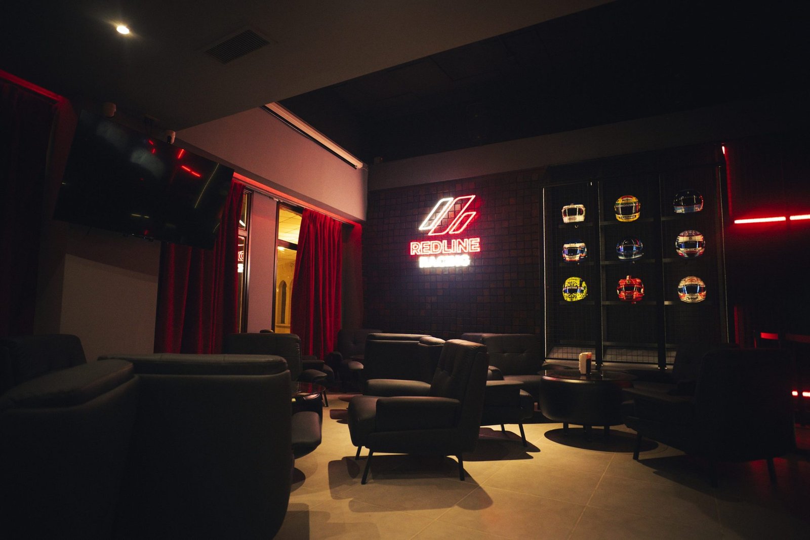 Lounge de Redline Racing con el cartel de neón y la vitrina de cascos