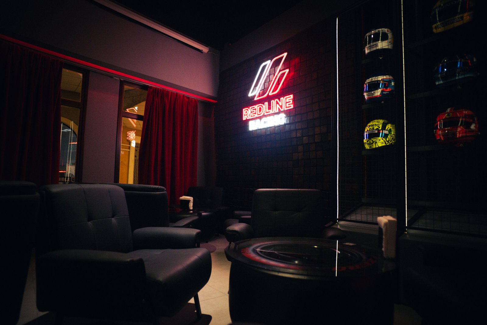 Lounge de Redline Racing con el cartel de neón y la vitrina de cascos