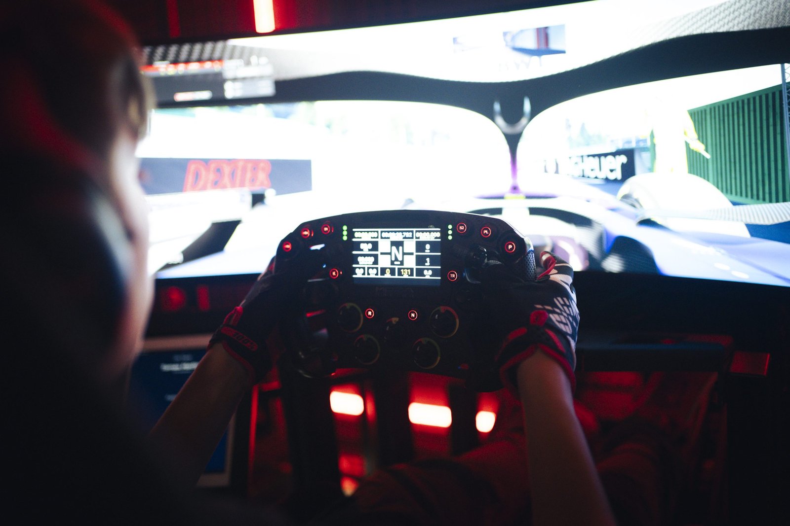 Piloto con guantes al volante de un simulador de Redline Racing